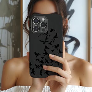 May include: A matte black smartphone case featuring a pattern of small, dark silhouettes of birds in flight scattered across the back surface. The case includes a cutout for a triple-lens camera system and a flash on the upper left corner.