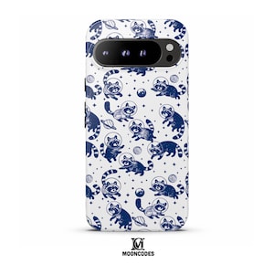 May include: White phone case featuring a navy blue pattern of raccoons in astronaut helmets, planets, and stars. The phone case has a black camera bar and the brand name "MOONCODES" at the bottom.