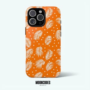 Puede incluir: Funda de teléfono naranja con un patrón de hojas y puntos blancos. La funda tiene un acabado brillante y presenta la marca "MOONCODES" en la parte inferior.