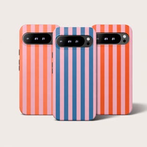Puede incluir: Tres fundas para teléfono con rayas verticales en varias combinaciones de colores. Una funda tiene rayas rosas y naranjas, otra rayas azules y rosas, y la tercera rayas naranjas y rosas. Las fundas tienen un recorte para la cámara y botones laterales.
