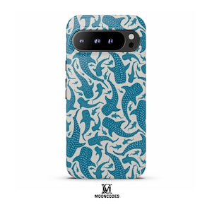 May include: A phone case featuring a repeating pattern of blue whale sharks with white polka dots on a cream background. The case has a camera cutout and the Mooncodes logo at the bottom.