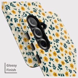 May include: Close-up of two phone cases with a glossy finish. The cases feature a cream-colored background with a repeating pattern of small yellow flowers and dark teal leaves. The text "Glossy Finish" is visible.
