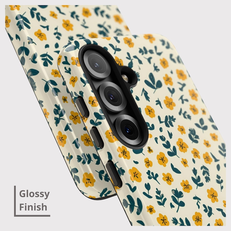May include: Close-up of two phone cases with a glossy finish. The cases feature a cream-colored background with a repeating pattern of small yellow flowers and dark teal leaves. The text "Glossy Finish" is visible.