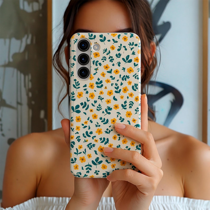 Phone case with small yellow wildflowers and green botanical leaves pattern on a light background, aesthetic floral design for Samsung models, slim protective cover.
