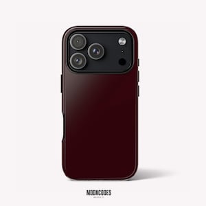 Puede incluir: Una funda para smartphone de color burdeos intenso con un módulo de cámara negro rectangular que incluye tres lentes circulares y un flash. La funda tiene un acabado liso de color sólido y está colocada verticalmente. El texto MOONCODES HOUSTON, TX está abajo.