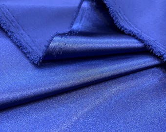 May include: Close-up of a vibrant blue fabric with a satin sheen. The fabric is folded, revealing the texture and sheen. The edges are raw, showing the fabric's weave. The color is a rich, saturated blue, suitable for apparel or home decor.