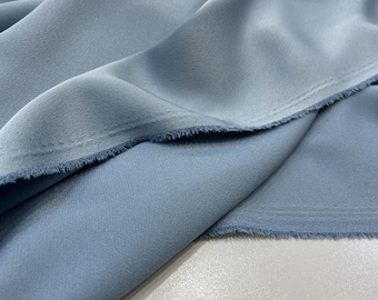 May include: A close-up of a light blue fabric with a slightly textured surface. The fabric is folded in half and the edges are raw.