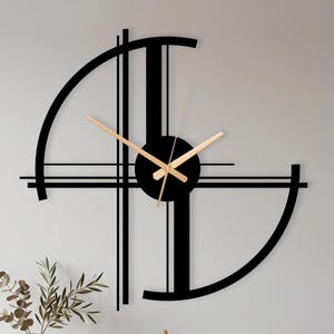 May include: A large black wall clock with a geometric design featuring two semi-circular arcs and intersecting vertical and horizontal lines. The clock has a central circular hub with thin, light-colored metallic hands for the hour and minute.