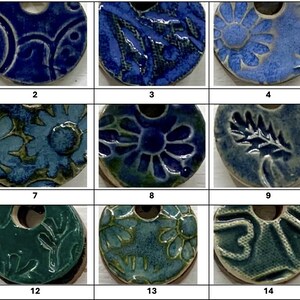 May include: A collection of fifteen ceramic pendants in various shades of blue and green. Each pendant features a unique embossed design, including floral, geometric, and abstract patterns. The pendants have a hole at the top for stringing.