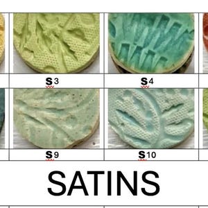 May include: A collection of twelve round ceramic tiles with textured patterns and various satin glaze finishes. Colors range from orange and yellow to green, blue, and purple. The word "SATINS" is printed below the tiles.