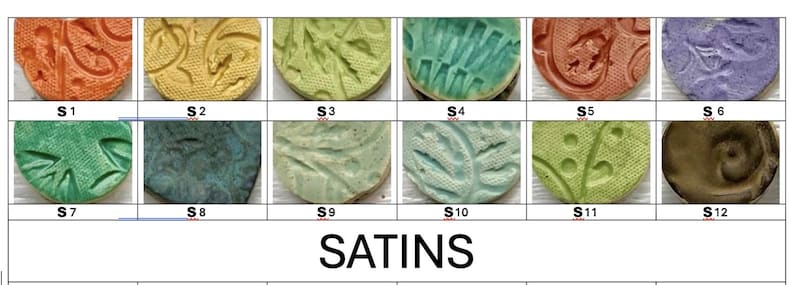 May include: A collection of twelve round ceramic tiles with textured patterns and various satin glaze finishes. Colors range from orange and yellow to green, blue, and purple. The word "SATINS" is printed below the tiles.