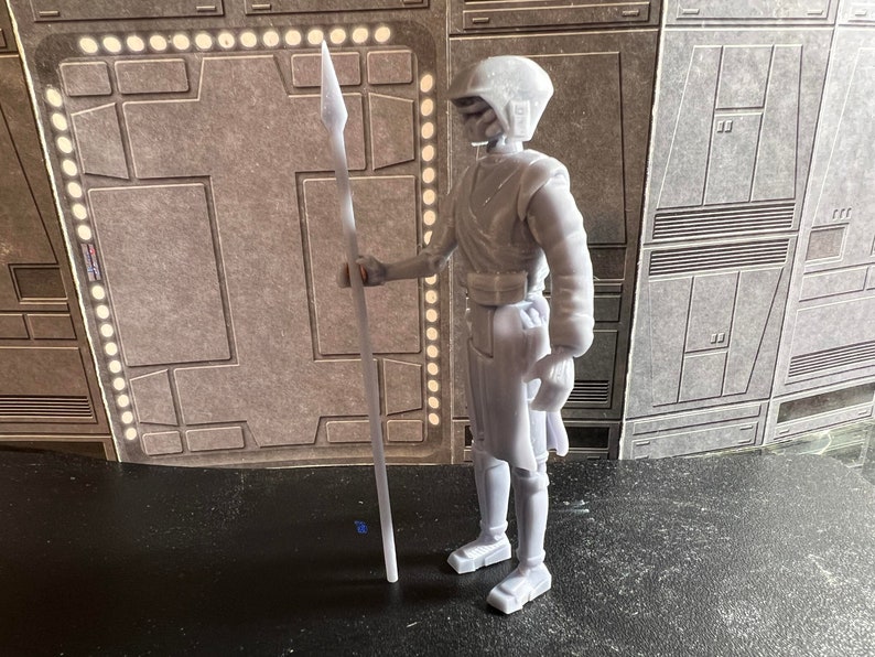 K&ouml;nnte beinhalten: Eine wei&szlig;e Plastik-Actionfigur eines Star Wars-Charakters, der eine Lanze h&auml;lt. Die Figur tr&auml;gt einen Helm und hat ein detailliertes Design.
