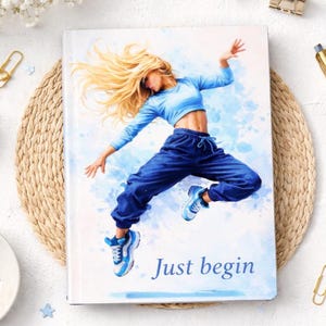 Op de afbeelding: Een hardcover notitieboek met een aquarel illustratie van een danser in de lucht. De danser draagt een blauwe crop top, een blauwe joggingbroek en blauwe sneakers. De woorden "Just begin" staan onderaan gedrukt.