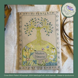 Può includere: Schema di punto croce di un albero con una casa tra i rami e le parole "Madre Natura" in un cerchio alla base. Lo schema è circondato da un bordo di lettere.