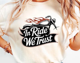 May include: Cream-colored sweatshirt featuring a black motorcycle graphic with flames and the text "In Ride We Trust" in a banner. The design includes a classic motorcycle silhouette.
