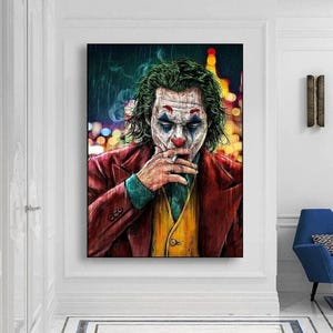 Puede incluir: Una impresión artística enmarcada que presenta un retrato del Joker. La obra de arte representa al personaje fumando un cigarrillo, con cabello verde, maquillaje blanco y un traje rojo. El fondo muestra luces borrosas de la ciudad.