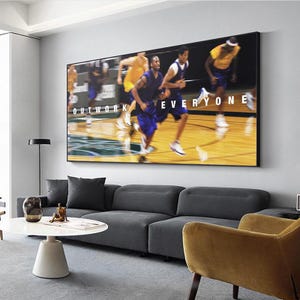 May include: A framed wall art print featuring a basketball game scene with players in motion. The image has the words "OUTWORK EVERYONE" in white text. The players are wearing blue and yellow uniforms, set against a blurred background.