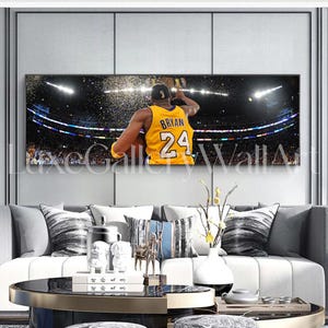 May include: A black and white photo of a basketball player wearing a yellow jersey with the name "BRYAN" and the number "24" on the back. The player is jumping in the air and holding a basketball. The photo is taken from behind the player and shows the player's back and the crowd in the background.