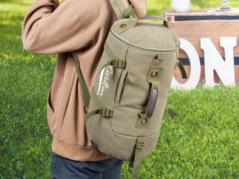 May include: A green canvas duffel bag with a brown leather handle and adjustable straps. The bag has a white embroidered logo that says "Cartier".