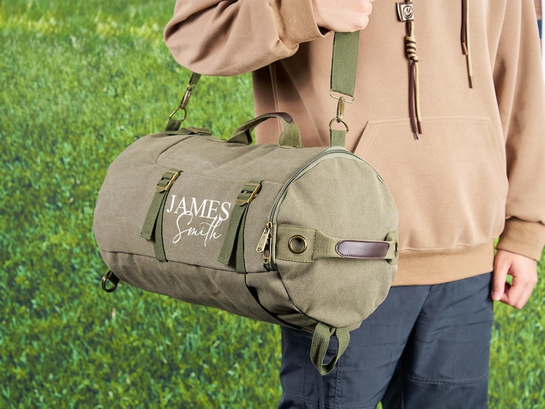 May include: A green canvas duffel bag with a brown leather handle and adjustable shoulder strap. The bag has a white embroidered name "JAMES Smith" on the front.