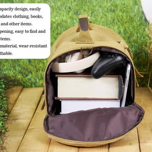 May include: A tan canvas duffel bag with a large opening and a brown interior. The bag is filled with books, headphones, and a video game controller. The bag is sitting on a wooden surface with green grass in the background. *Large capacity design, easily accommodates clothing, books, toiletries and other items. *Large opening, easy to find and take out items. *Canvas material, wear-resistant and breathable.