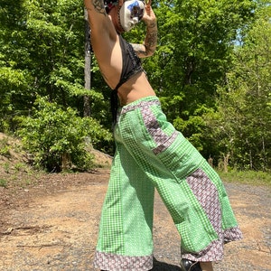May include: Green and white gingham trousers with brown and white patterned trim. The trousers have a patchwork design and are wide-legged.