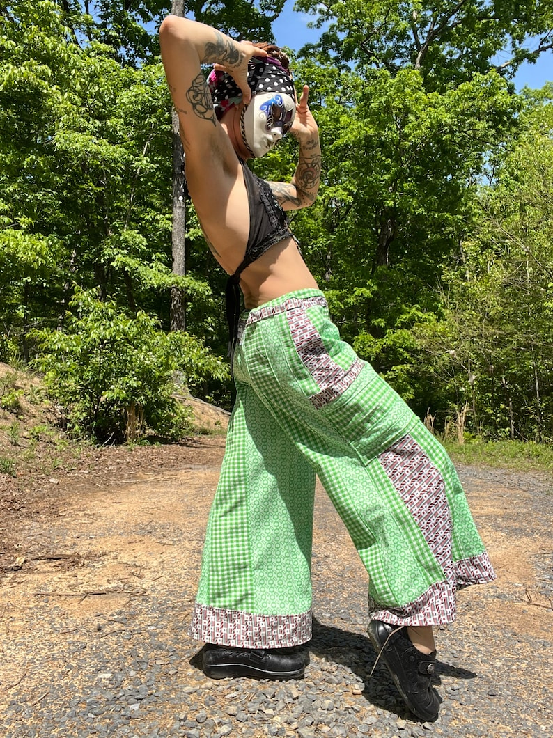 May include: Green and white checkered pants with brown and white patterned trim. The pants have a patchwork design and are wide-legged.