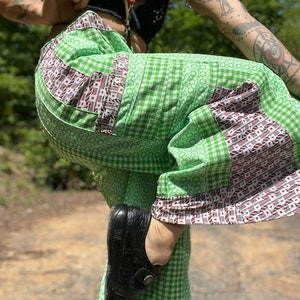 May include: Green and white checkered pants with red and white trim. The pants are made of a lightweight fabric and have a wide leg.