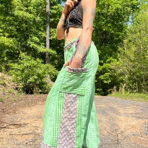 May include: Green and white checkered pants with a brown and white patterned panel on the side. The pants have a large pocket on the side and a ruffle at the bottom.
