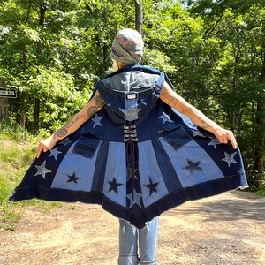 May include: A denim vest with a hooded cape featuring a star pattern. The vest is made of different shades of blue denim and has a lace-up back.