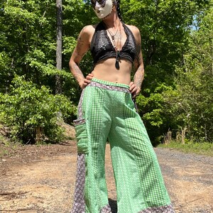 May include: Green and white gingham wide-leg pants with a floral pattern on the side. The pants have a brown and white trim around the bottom and waist.