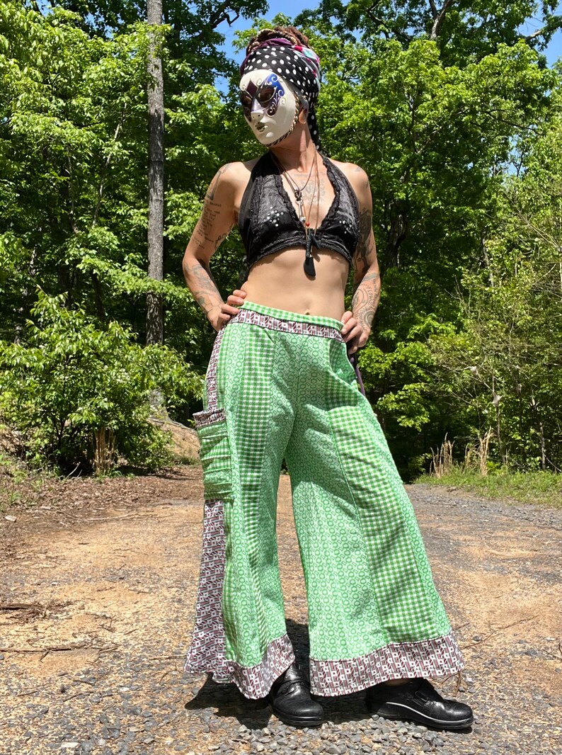 May include: Green and white gingham wide-leg pants with a floral pattern on the side. The pants have a brown and white trim around the bottom and waist.