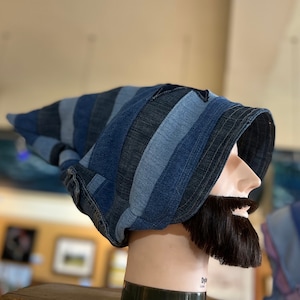 Pode incluir: Um chapéu de brim azul com um padrão listrado. O chapéu está em uma cabeça de manequim com uma barba marrom.