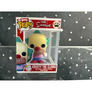 May include: A Bitty Pop! vinyl figure of Krusty the Clown from The Simpsons. The figure has a yellow head, red nose, and green hair. It is packaged in a clear plastic display case with the show's logo and character name.