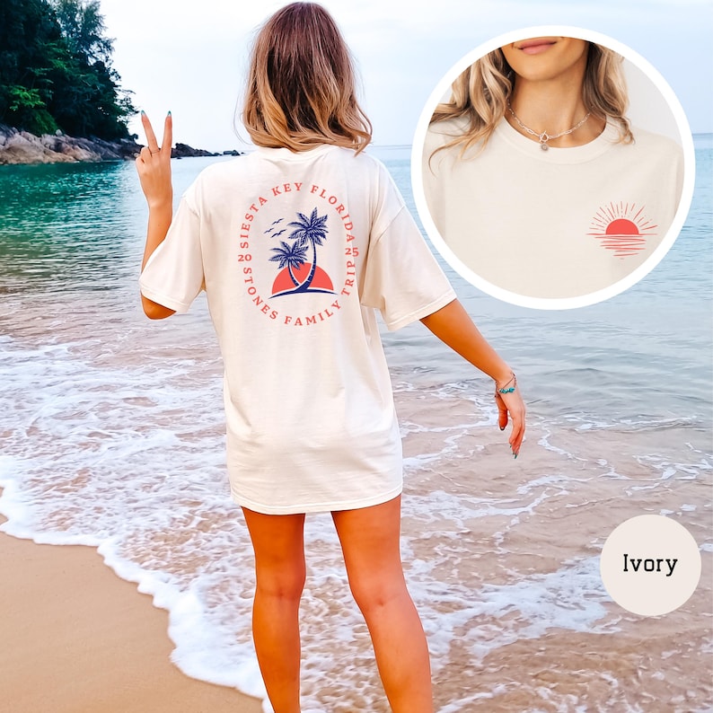 Może przedstawiać: Biały t-shirt z nadrukiem z tyłu, kt&oacute;ry m&oacute;wi "Siesta Key Florida Family Trip 2020" z palmami i zachodem słońca. Koszulka jest pokazana na modelce stojącej na plaży.