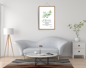 Puede incluir: Un estampado enmarcado con un diseño de acuarela de hojas verdes y el texto "A Heart of Love". El estampado cuelga sobre un sofá gris claro en un salón. La habitación incluye una lámpara blanca, una mesa de centro redonda y una mesita auxiliar.