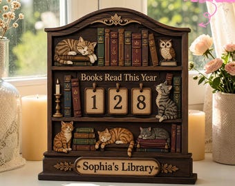 May include: A dark brown wooden bookshelf tracker with three shelves, featuring miniature cats, an owl, and stacked books. The center shelf displays the text Books Read This Year with three number tiles showing 128. Sophia's Library is engraved below.