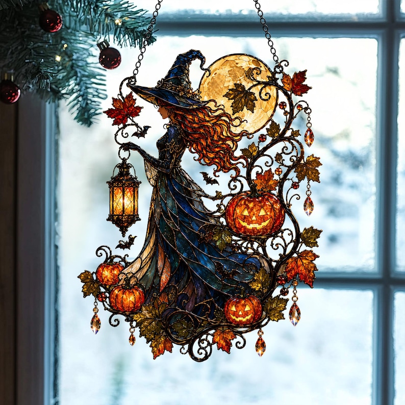 May include: A stained glass suncatcher featuring a witch in a blue hat and gown holding a glowing lantern. The design includes a large yellow moon, orange jack-o'-lanterns, autumn leaves, and small bats, all framed by intricate metal scrollwork.