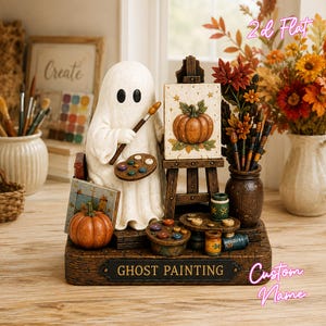May include: A decorative figurine featuring a white ghost holding a paintbrush and palette, standing before an easel with a pumpkin painting. The base is labeled GHOST PAINTING and includes miniature art supplies, a pumpkin, and a vase of flowers.