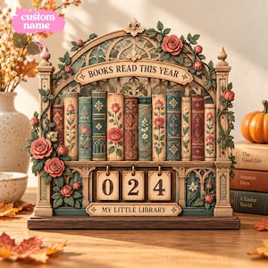 Könnte beinhalten: Ein dekorativer Lese-Tracker aus Holz mit einem verzierten Bogenrahmen und geschnitzten Rosen, beschriftet mit "BOOKS READ THIS YEAR" und "MY LITTLE LIBRARY", inklusive drei hängenden Holzplättchen, die die Zahl 024 anzeigen.