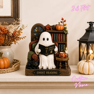 May include: A decorative figurine featuring a white ghost sitting in a brown armchair, reading a book titled GHOST STORIES. A black cat rests at the base, next to a bookshelf, a small pumpkin, a jack-o'-lantern mug, and a plaque reading GHOST READING.