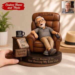 May include: A custom figurine of an older person with glasses sleeping in a brown armchair. The chair is engraved with the name William. A side table holds a mug labelled Nap Like a Legend and a newspaper. The base reads Official Member of the Just Resting My Eyes Club.