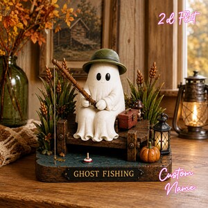 May include: A decorative figurine of a white ghost wearing a green hat, sitting on a wooden bench while holding a fishing rod. The base features a dark blue water surface, a small pumpkin, a lantern, and a plaque with the text GHOST FISHING.