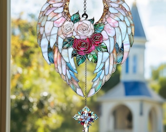 May include: Stained glass angel wings suncatcher with a floral arrangement of roses in shades of pink and red. The wings have iridescent details and gold accents. A decorative cross hangs below, suspended by a chain.
