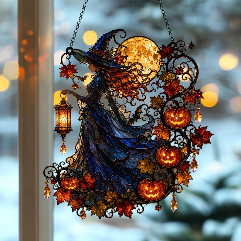 May include: A stained glass suncatcher featuring a witch in a blue gown and pointed hat holding a glowing lantern. The design includes a large yellow moon, orange jack-o'-lanterns, and red autumn leaves, all framed by black metal scrollwork.