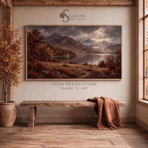 Op de afbeelding: Een rechthoekig ingelijst digitaal landschapsschilderij met een bergketen, een kalm meer en herfstbladeren in oranje en bruine tinten. De tekst Seasons Art House en High Resolution Frame TV Art is zichtbaar op de muur.