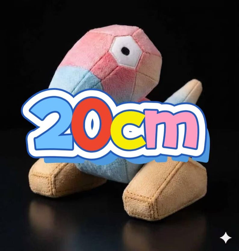 May include: A soft toy in the shape of a geometric figure, with pink, blue, and white panels. The toy has a large eye and tan feet. The text "20cm" is displayed in a blue, red, yellow, and pink bubble.