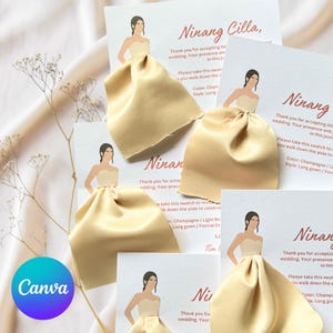 May include: Several wedding invitation cards with a light beige satin fabric swatch. Each card has a drawing of a woman in a formal dress and handwritten text. The cards are arranged on a light-coloured fabric.