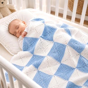 Può includere: Un bambino che dorme in una culla è coperto da una coperta fatta a mano con un motivo quadrato. La coperta presenta un motivo a scacchiera di quadrati bianchi e azzurri. Un orsacchiotto è visibile sullo sfondo.