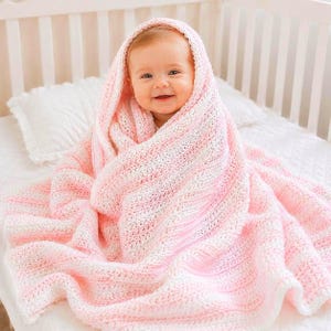 May include: A baby wrapped in a soft, textured crochet blanket featuring alternating horizontal stripes of pale pink and white yarn. The blanket has a consistent, repeating knit pattern throughout, providing a cozy, layered appearance around the infant.